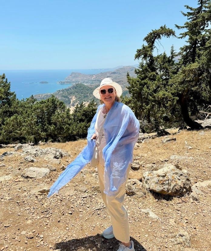 Woman wearing Ovcio scarf on a scenic coastal hillside